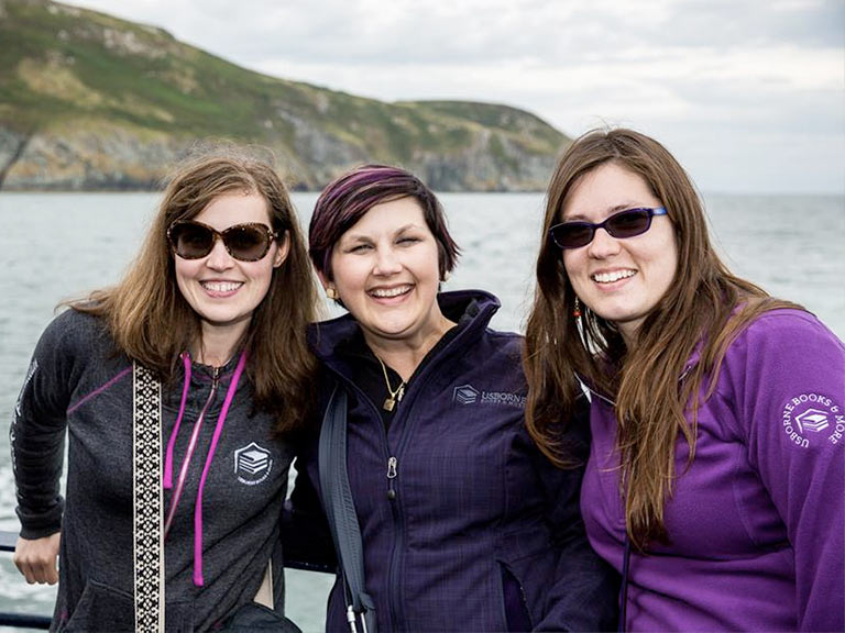 Three women on a boat wearing branded apparel